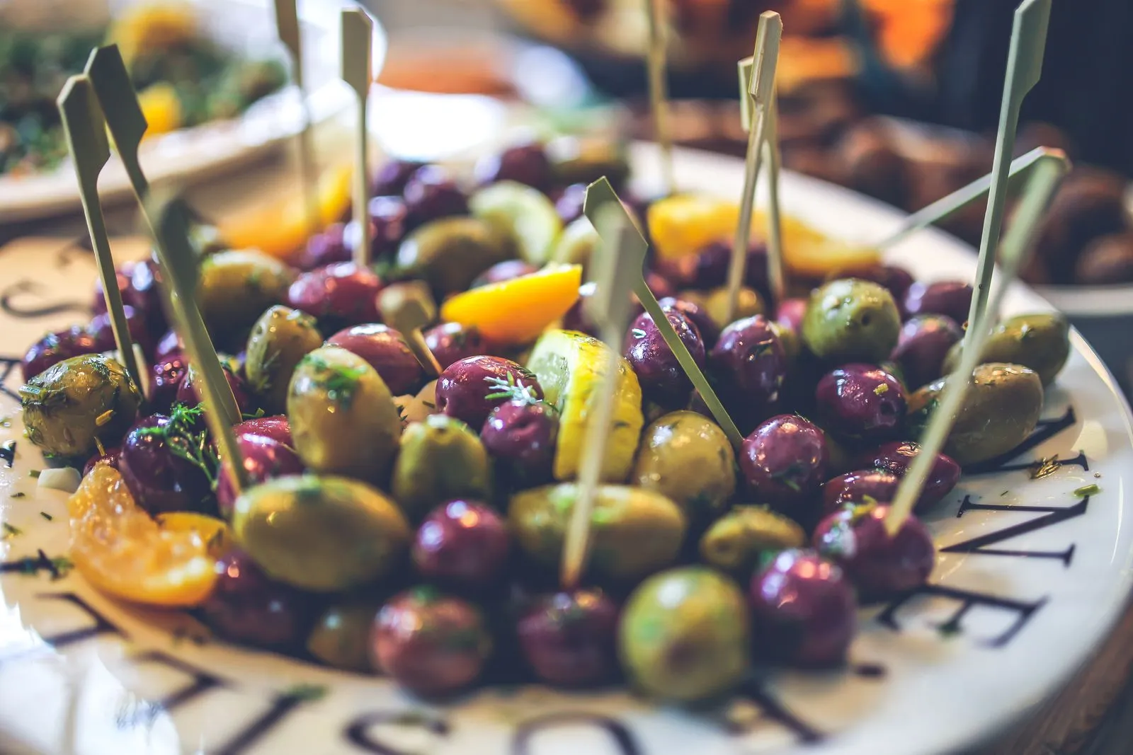 Close-up of assorted olives with skewers on a plate, perfect for healthy and tasty meals.